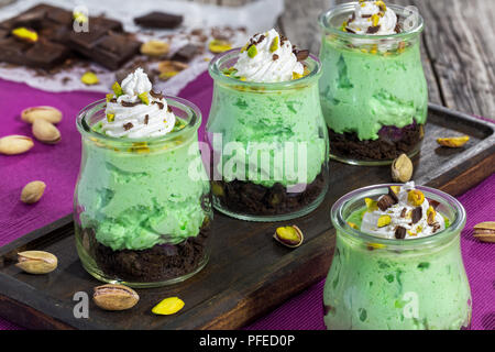 Pistache un cheesecake sans cuisson - Bagatelle en verre multicouche maison facile dessert pour fête ou dîner en famille sur planche de bois foncé, close-up Banque D'Images