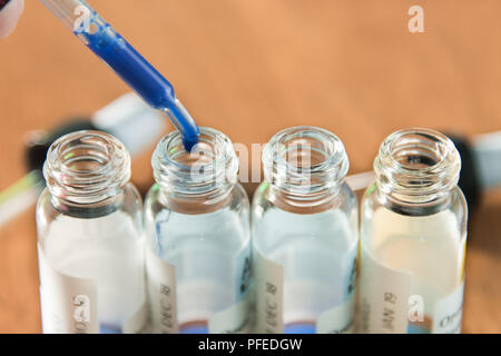 L'ajout d'éléments en verre de laboratoire drop à l'une des éprouvettes. Une expérience scientifique dans un laboratoire de recherche scientifique. Banque D'Images