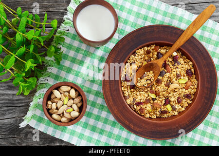 Délicieux petit déjeuner sain - partie de granola fait maison avec des fruits confits et des écrous dans la plaque d'argile. menthe, tasse de lait dans un bol de pistaches et sur Banque D'Images