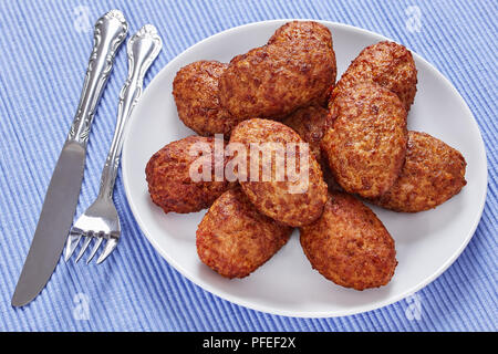 Escalopes de délicieux plats de viande juteuse sur plaque blanche sur tapis de table avec fourchette et couteau sur de vieilles cartes de la peinture rustique, close-up Banque D'Images