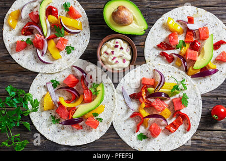 Délicieux fajitas sain avec des morceaux de saumon fumé, tranches d'avocat, le poivron, l'oignon, le persil avec de la crème en petite cuvette d'argile sur vieux dark woo Banque D'Images