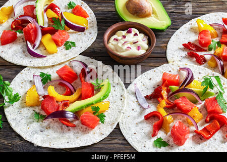 Délicieux fajitas sain avec des morceaux de saumon fumé, tranches d'avocat, le poivron, l'oignon, le persil avec de la crème en petite cuvette d'argile sur vieux dark woo Banque D'Images