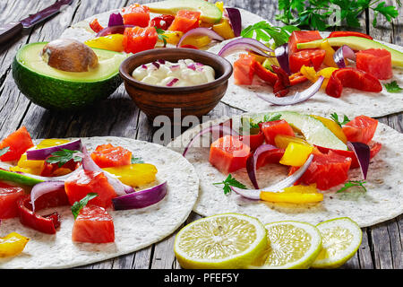 Délicieux fajitas sain avec des morceaux de saumon fumé, tranches d'avocat, le poivron, l'oignon, le persil avec de la crème dans de petits cuvette d'argile sur vieux dark wo Banque D'Images