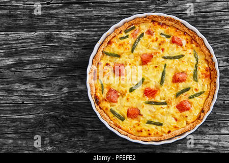 Filets de saumon Quiche aux pièces, l'Emmental, la crème sure, le haricot vert et l'oignon dans le plat de cuisson sur la vieille table en bois, close-up, vue d'en haut Banque D'Images