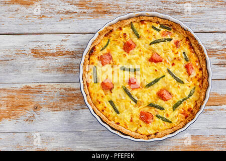 Tarte quiche délicieux saumon farci aux haricots verts,et l'Emmental, la crème, l'oignon et les œufs dans le plat de cuisson sur la vieille table en bois blanc, vue depuis l'ab Banque D'Images