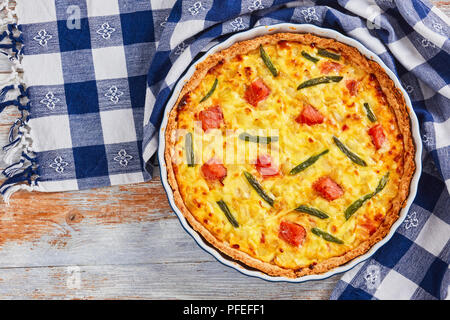 Quiche au saumon et haricots verts Tarte fine à l'Emmental, la crème, l'oignon et les œufs dans le plat de cuisson sur la vieille table en bois avec des serviettes de cuisine, close-up, voir fr Banque D'Images