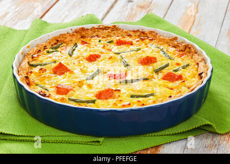 Quiche au saumon et haricots verts Tarte fine à l'Emmental, la crème, l'oignon et les œufs dans le plat de cuisson sur le tableau vert mat sur la vieille table en bois, close-up, voir fr Banque D'Images