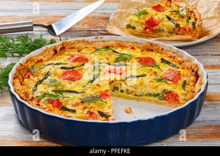 Quiche au saumon, français avec haricots verts et de l'Emmental, la crème, l'oignon et les œufs coupés en tranches dans le plat de cuisson. spatule à gâteau et un morceau de la tarte sur Banque D'Images