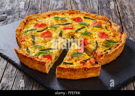 Quiche maison délicieux avec le saumon, le haricot vert et l'Emmental, la crème, l'oignon et les œufs coupés en tranches sur la plaque en ardoise sur l'ancien en bois bo Banque D'Images