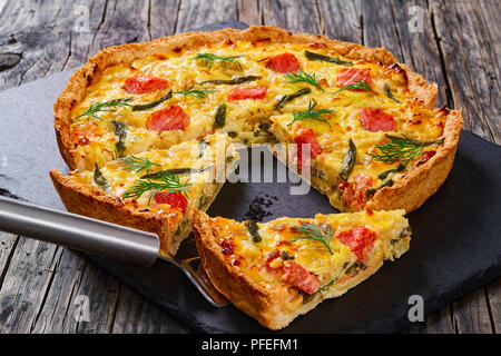 Délicieux avec le saumon, quiche français haricot vert et l'Emmental, la crème, l'oignon et les œufs coupés en tranches sur la plaque en ardoise. morceau de tart sur spatule, vie Banque D'Images