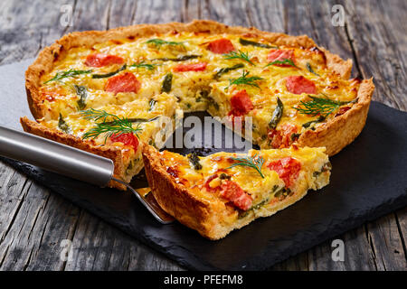 Maison délicieux saumon quiche aux Français, haricot vert et l'Emmental, la crème, l'oignon et les œufs coupés en tranches sur la plaque en ardoise. morceau de tart sur spa Banque D'Images