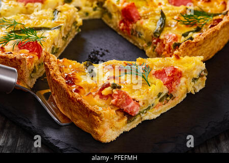 Maison délicieux saumon quiche aux Français, haricot vert et l'Emmental, la crème, l'oignon et les œufs coupés en tranches sur la plaque en ardoise. morceau de tart sur spa Banque D'Images