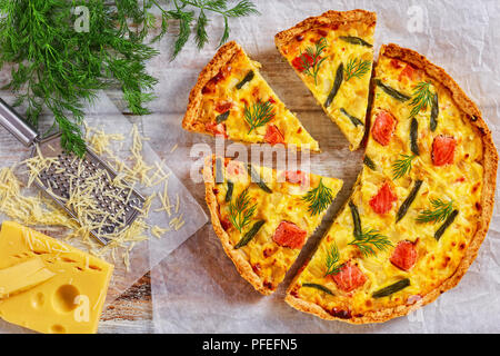 Maison délicieux saumon quiche aux Français, haricot vert et l'Emmental, la crème, l'oignon et les œufs coupés en tranches sur du papier sulfurisé. morceau de tart sur gr Banque D'Images