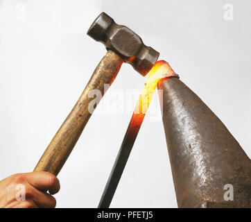 Red-hot steel bar étant façonné avec un marteau, vue de côté. Banque D'Images