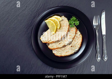 Carpe juive ou émincé de poisson farci la farcissure prг©parent à l'intérieur de la peau de poisson, coupés en tranches et servi sur la plaque noire avec les tranches de citron sur le plateau en pierre avec une fourche Banque D'Images