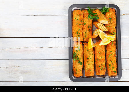 Panés croustillants délicieux poulet haché cuit Chimichangas ensemble et coupées en deux, saupoudrées de persil finement haché et les tranches de citron dans la cuisson dis Banque D'Images