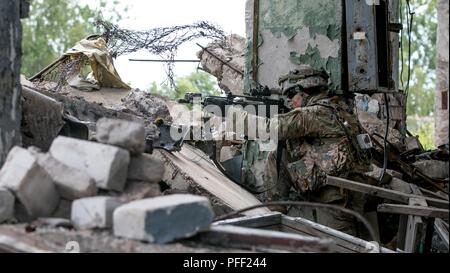 Des cadets de l'armée américain Kenneth basse, un cadet qui étudient à l'Université d'Utah Valley, qui nous commande des cadets de l'armée, Fort Knox, Ky., prend une position défensive offensive militaire au cours de l'entraînement en milieu urbain (MOUT) tout en participant à la grève 18 Sabre de Skrunda, Lettonie, 12 juin, 2018. Grève de sabre est un exercice multinational en ce moment à sa huitième année. L'exercice de cette année, dont la durée est prévue à partir de juin 3-15, essais des participants de 19 pays sur leur capacité à travailler ensemble pour promouvoir la stabilité dans la région et d'améliorer les unités de chaque capacité d'accomplir leurs missions. désignés Banque D'Images