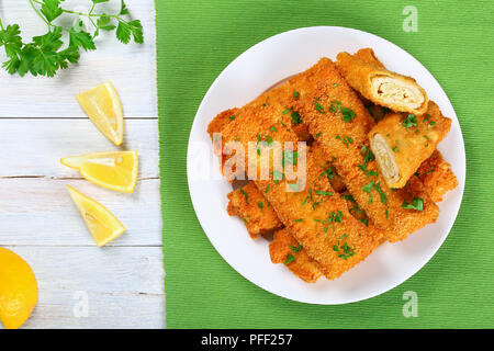 Panés croustillants délicieux poulet haché cuit les enchiladas déroulables ensemble et les couper en deux sur la plaque blanche, de tranches de citron et le persil sur table en bois, vue Banque D'Images