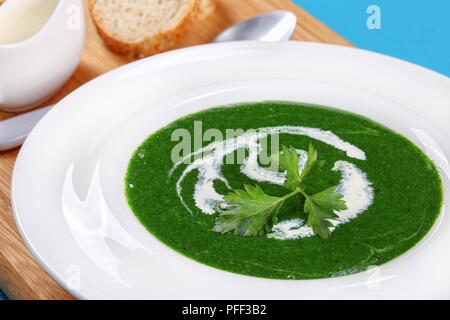 Close-up de l'été dans la soupe d'épinards sain large rebord assiette à soupe sur tableau blanc, à la crème et les noix de pin sur une planche à découper, vue d'en haut Banque D'Images