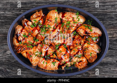 Ailes de poulet crues marinées au miel, sauce soja, les épices saupoudrées de persil finement haché dans un plat ovale, recette asiatique, vue de dessus, cl Banque D'Images