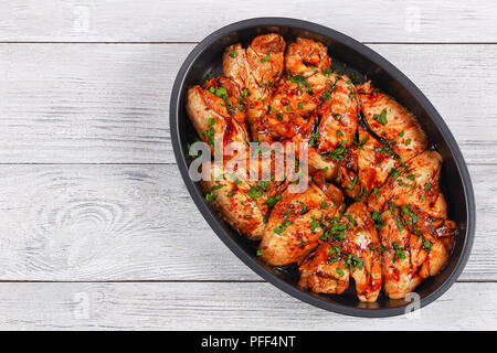 Ailes de poulet crues marinées au miel, sauce soja, les épices saupoudrées de persil finement haché dans un moule ovale préparé pour rôti, recette asiatique, v Banque D'Images