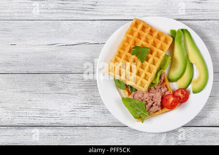 De délicieuses gaufres salé sandwich avec tranches d'avocat, le pâté de foie de la Turquie, la laitue, les épinards et le persil sur plaque blanche avec des tomates cerises, des vi Banque D'Images