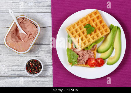 De délicieuses gaufres salé sandwich avec tranches d'avocat, le pâté de foie de la Turquie, la laitue, les épinards, les tomates cerise et le persil sur plaque blanche, simplement Banque D'Images
