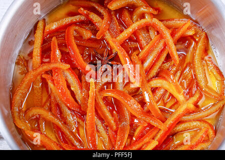 Close-up of orange et citron confits Maison cuit dans du sirop d'écorces de cannelle, muscade et anis étoile en pot, vue de dessus Banque D'Images