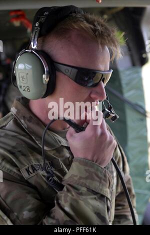 Texas Army National Guard de la CPS. William P. Kaserman, un étudiant en Master en rappel, parle à l'Oregon Army National Guard pilotes de plus son casque radio HH-60M à bord d'un hélicoptère Black Hawk au cours de l'appareil de test de commandement et de contrôle, le 13 juin 2018 au Camp Rilea près de Warrenton, Oregon. Kaserman envoyé avec succès le rappel des soldats de l'avion vers le bas 90-pieds au sol dans le cadre de l'essai. ( Banque D'Images