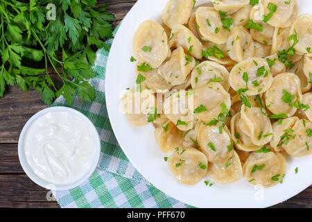 Beignets de viande chaud maison de farine complète ou saupoudré de pelmeni russes de persil sur plaque blanche sur table en bois foncé avec du persil et ainsi Banque D'Images