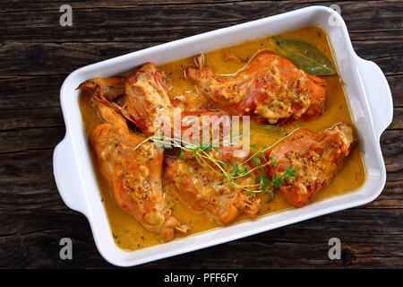 Délicieux Lapin cuisiné à la moutarde de Dijon et le vin blanc ou un lapin à la moutarde plat à gratin sur la vieille table en bois foncé, authentique recette française, vie Banque D'Images