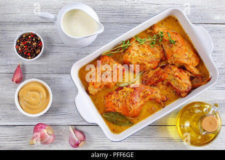 Délicieux Lapin cuisiné à la moutarde de Dijon, sauce crème et vin blanc ou un lapin à la moutarde plat à gratin sur la vieille table en bois avec ingrédients sur b Banque D'Images