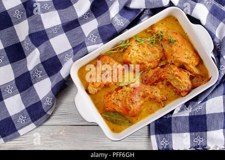 Délicieux Lapin cuisiné à la moutarde de Dijon, sauce crème et vin blanc ou un lapin à la moutarde plat à gratin sur la vieille table en bois avec une serviette, cuisine Banque D'Images