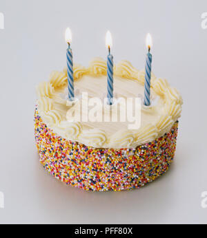 Gâteau glacé décoré avec des centaines et des milliers et trois des bougies allumées, Close up. Banque D'Images