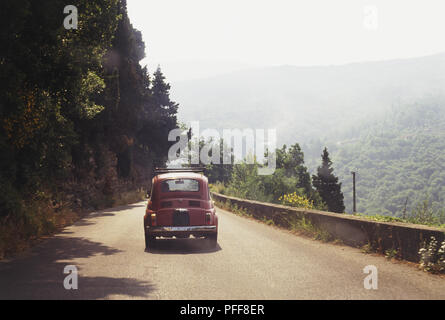 L'Italie, l'Est de la Toscane, nr Borgo San Lorenzo, petit rouge voiture roulant sur route de montagne, Vue de derrière Banque D'Images
