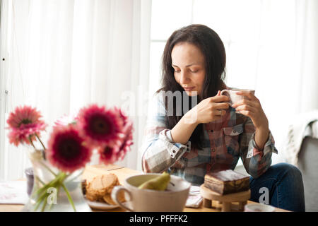 Femme avec une tasse de café, un bon matin à la maison. Le petit-déjeuner et café parfumé. L'intérieur est confortable et les fleurs. Espace libre pour le texte. Banque D'Images