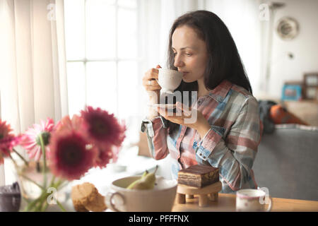 Femme avec une tasse de café, un bon matin à la maison. Le petit-déjeuner et café parfumé. L'intérieur est confortable et les fleurs. Espace libre pour le texte. Banque D'Images