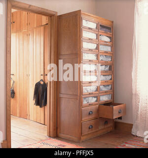 Placard à façade en verre au-dessus du pain sur le plan de travail dans la  petite cuisine avec de la vaisselle sur l'étagère au-dessus de casseroles  en rack mural en bois Photo