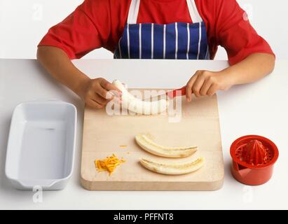 Couper les bananes épluchées dans la moitié de la longueur, de zeste d'orange râpé et centrifugeuse à proximité (fabrication de bananes cuites au four), close-up Banque D'Images