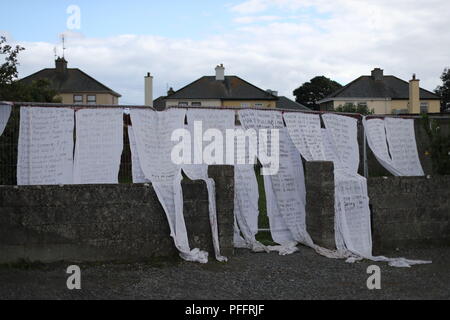 Draps de l'hôtel avec le nom de centaines d'enfants décédés drapés sur les portes d'un lieu de sépulture d'une masse à Tuam, Co Galway où une veillée aura lieu lors de la visite du pape à Knock Shrine à Mayo. Banque D'Images