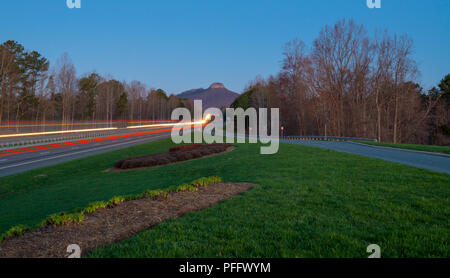 Dans la distance de Pilot Mountain au vu de l'oublier sur l'autoroute. Les sentiers de la lumière des voitures qui vont et viennent. Banque D'Images