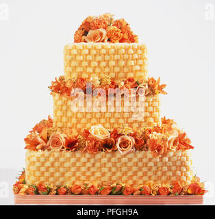 Gâteau de mariage traditionnel américain à trois niveaux, gâteau, glaçage buttercream lprpdé dans panier-weave pattern, fleurs fraîches poussé entre les couches de gâteau, vue de face. Banque D'Images