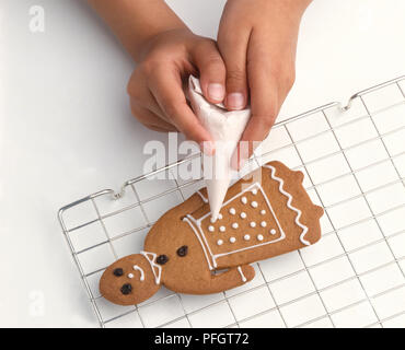 Girl's hands sur le givrage de la tuyauterie d'épices biscuit sur grille de refroidissement, close-up Banque D'Images