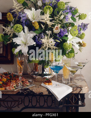 Fleurs dans un vase, divers cocktails et canapés disposés sur le tableau Banque D'Images