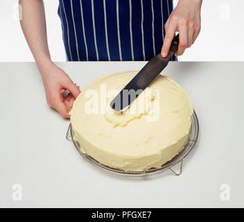 La diffusion de fromage fondu sur le dessus d'un gâteau de carotte Banque D'Images
