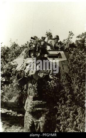 Waffen-SS Grenadier devant lourdement camouflé Halftrack avec 20mm 1944 Banque D'Images