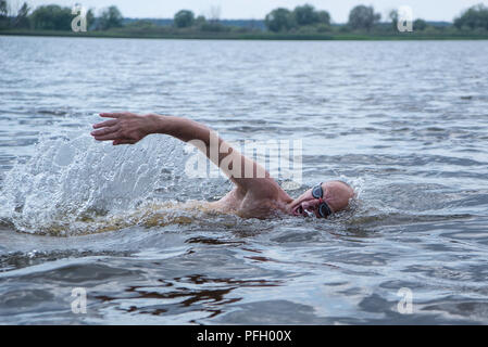Un vieil homme musclé à lunettes de natation nage avec un style crawl Banque D'Images