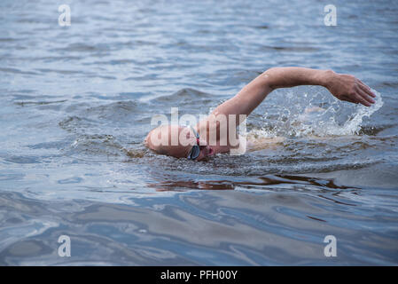 Un vieil homme musclé à lunettes de natation nage avec un style crawl Banque D'Images