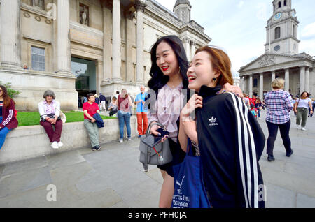 Deux jeunes femmes japonaises à l'adoption de la National Gallery, Trafalgar Square, Londres, Angleterre, Royaume-Uni. St Martin dans les champs derrière l'église Banque D'Images