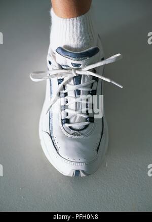 Le pied d'une femme en blanc la chaussure de sport en cuir avec lacets attachés, close-up Banque D'Images